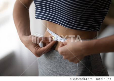 Close up woman using measurement tape, measuring waist, weight loss Close up woman using measurement tape, measuring waist, weight loss 80914963