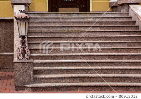 marble staircase with stone steps and iron forged lantern in a retro style, close-up of the architecture of the house with street lighting, nobody. marble staircase with stone steps and iron forged lantern in a retro style, close-up of the architecture of the house with street lighting, nobody. 80915012