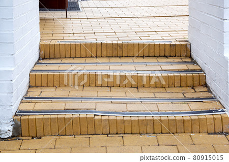 steps with rubber non-slip strips on the arch staircase at the entrance to the white brick building close-up, nobody. 80915015