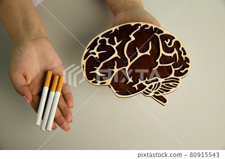 Wooden model of brain and cigarette in the hands of a nurse. Top view 80915543