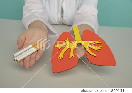 Wooden model of lung and cigarette in the hands of a nurse. Smoking addiction 80915544