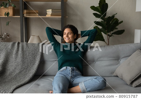 Smiling attractive young woman leaning back on cozy couch 80915787