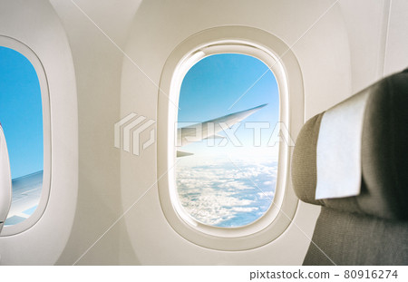 Inside of a plane window view of wing during flight of airplane interior with seat background 80916274
