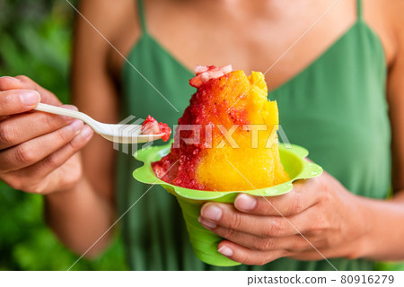 Shave Ice Hawaii local food woman eating hawaiian shaved ice cream treat in Honolulu Waikiki beach, Hawaii, USA 80916279