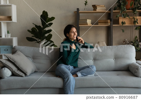 Smiling woman talking on phone, enjoying conversation, sitting on couch Smiling woman talking on phone, enjoying conversation, sitting on couch 80916687