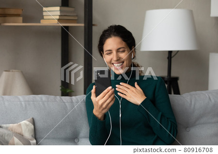 Close up happy woman in earphones chatting on phone online Close up happy woman in earphones chatting on phone online 80916708