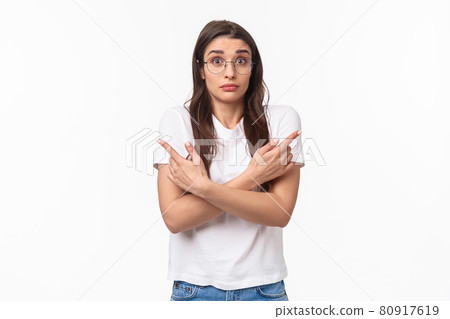 Waist-up of indecisive, clueless good-looking caucasian female in glasses, cant decide, pointing fingers sideways left and right, shrugging and looking confused, asking for help in taking decision Waist-up of indecisive, clueless good-looking caucasian female in glasses, cant decide, pointing fingers sideways left and right, shrugging and looking confused, asking for help in taking decision 80917619