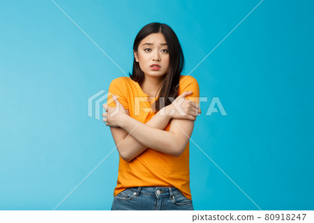 Girl feeling uncomfortable walking light yellow t-shirt, hugging herself trembling, shaking feeling cold, freezing windy weather, frowning grimacing discomfort, stand blue background Girl feeling uncomfortable walking light yellow t-shirt, hugging herself trembling, shaking feeling cold, freezing windy weather, frowning grimacing discomfort, stand blue background 80918247