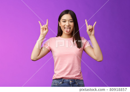 Rebellious amused asian girl enjoy rock-n-roll, attend awesome concert have fun, show tongue make heavy-metal gesture, express excitement and joy, stand purple background cheerful Rebellious amused asian girl enjoy rock-n-roll, attend awesome concert have fun, show tongue make heavy-metal gesture, express excitement and joy, stand purple background cheerful 80918857