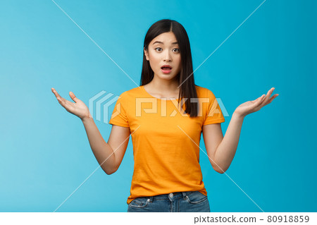 Questioned unaware young asian girl with dark short haircut shrugging hands spread sideways, look confused open mouth uncertain, being clueless, stand blue background wear yellow t-shirt Questioned unaware young asian girl with dark short haircut shrugging hands spread sideways, look confused open mouth uncertain, being clueless, stand blue background wear yellow t-shirt 80918859