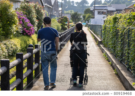 一對夫婦推著嬰兒車走在小溪旁的小路上 80919468