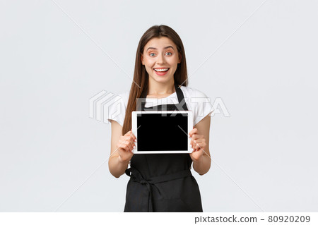 Grocery store employees, small business and coffee shops concept. Surprirsed happy and excited female barista showing great news on digital tablet display, rejoicing over new promo special offer 80920209