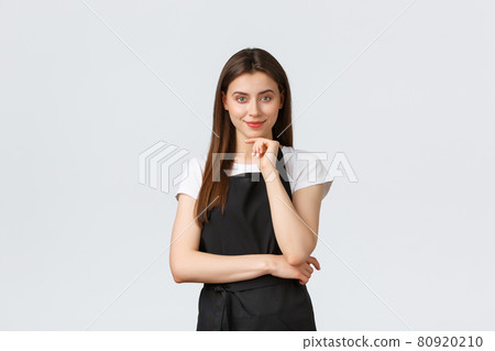 Small business, employees and coffee shop concept. Pleased confident female barista smiling intrigued. Satisfied thoughtful saleswoman having idea. Waiter listening interesting plan 80920210
