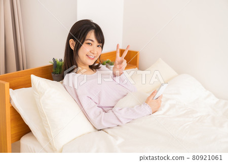 一名婦女在床上的看一個智能手機 一名婦女在床上的看一個智能手機 80921061