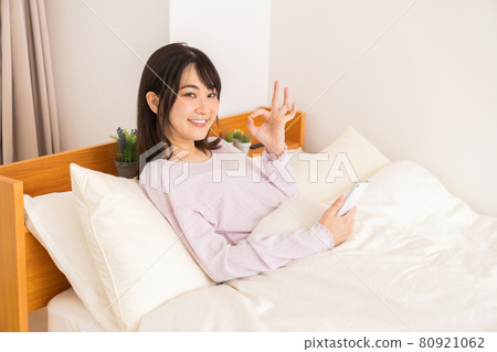 一名婦女在床上的看一個智能手機 一名婦女在床上的看一個智能手機 80921062