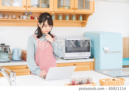 I think of a woman watching a personal computer in the kitchen I think of a woman watching a personal computer in the kitchen 80921114