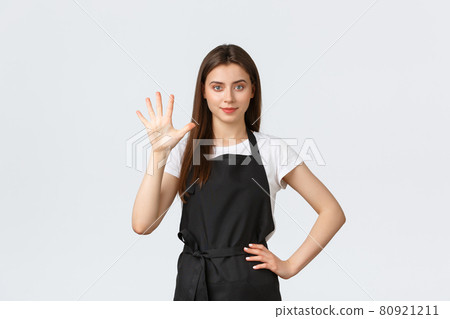 Grocery store employees, small business and coffee shops concept. Cheerful young female barista in black apron showing number five, smiling determined, working in cafe 80921211
