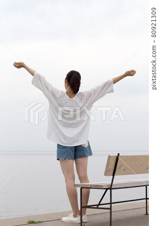 Back view of a woman stretching while looking at the sea on a summer morning 80921309