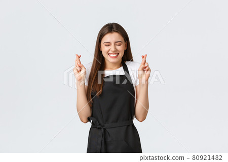 Grocery store employees, small business and coffee shops concept. Excited and cheerful beautiful female barista in black apron smiling optimistic, cross fingers good luck, making wish Grocery store employees, small business and coffee shops concept. Excited and cheerful beautiful female barista in black apron smiling optimistic, cross fingers good luck, making wish 80921482