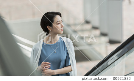 A woman riding an escalator A woman riding an escalator 80921883