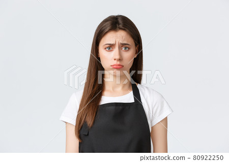 Employees, job employment, small business and coffee shop concept. Gloomy disappointed female barista, cashier in black apron frowning uneasy, pouting troubled over white background Employees, job employment, small business and coffee shop concept. Gloomy disappointed female barista, cashier in black apron frowning uneasy, pouting troubled over white background 80922250