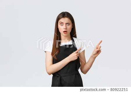 Small business, employees and coffee shop concept. Confused barista in black apron frowning and looking concerned as pointing upper right corner worried, standing white background Small business, employees and coffee shop concept. Confused barista in black apron frowning and looking concerned as pointing upper right corner worried, standing white background 80922251