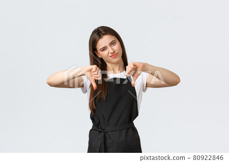 Grocery store employees, small business and coffee shops concept. Skeptical and disappointed waitress in black apron smirk displeased and showing thumbs-down, white background 80922846