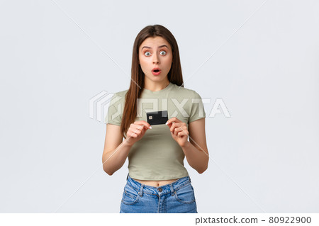 Shopping mall, lifestyle and fashion concept. Shocked and astonished caucasian female buyer, customer in store holding credit card and stare surprised at awesome special discounts Shopping mall, lifestyle and fashion concept. Shocked and astonished caucasian female buyer, customer in store holding credit card and stare surprised at awesome special discounts 80922900