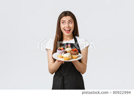 Grocery store employees, small business and coffee shops concept. Friendly smiling waitress bring desserts to cafe vistitor. Smiling cute barista showing delicious cupcakes on menu 80922994