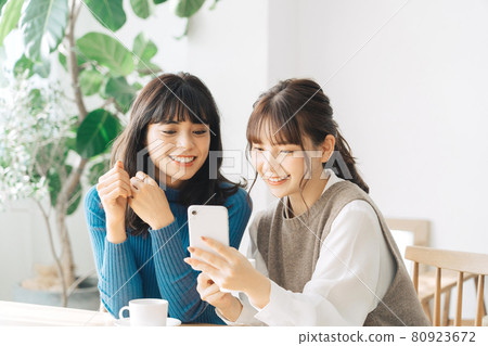 看智能手機的兩名微笑的婦女在咖啡館 80923672