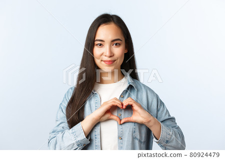 Lifestyle, people emotions and beauty concept. Smiling lovely asian woman confess love or sympathy, like something. Girl showing heart sign over chest, standing white background 80924479