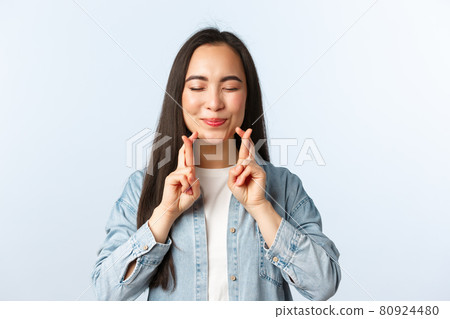Lifestyle, people emotions and beauty concept. Optimistic hopeful asian woman in casual outfit making wish with closed eyes and fingers crossed, smiling as having faith dreams come true Lifestyle, people emotions and beauty concept. Optimistic hopeful asian woman in casual outfit making wish with closed eyes and fingers crossed, smiling as having faith dreams come true 80924480