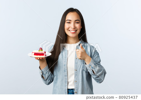 Social distancing lifestyle, covid-19 pandemic, celebrating holidays during coronavirus concept. Happy cheerful asian female show thumbs-up and smiling, holding delicious cake dessert Social distancing lifestyle, covid-19 pandemic, celebrating holidays during coronavirus concept. Happy cheerful asian female show thumbs-up and smiling, holding delicious cake dessert 80925437