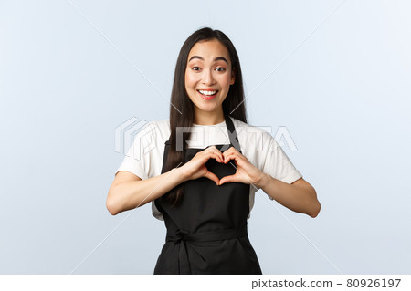 Coffee shop, small business and startup concept. Cute and caring young asian female cafe employee love coworkers or clients, showing heart sign over chest, wearing black apron Coffee shop, small business and startup concept. Cute and caring young asian female cafe employee love coworkers or clients, showing heart sign over chest, wearing black apron 80926197
