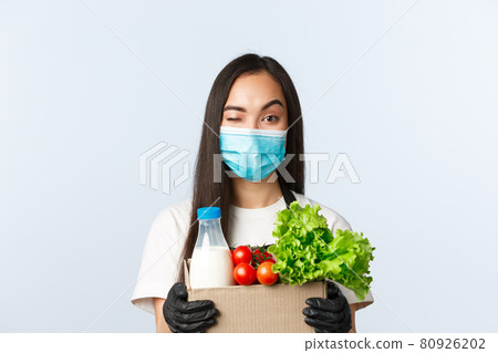 Covid-19, grocery store, employment, small business and preventing virus concept. Smiling asian female shop manager, cashier in medical mask and gloves, taking care of your food order 80926202