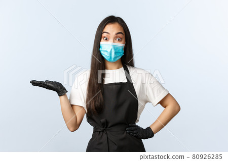 Covid-19, social distancing, small coffee shop business and preventing virus concept. Surprised asian female cafe staff, barista in medical mask and gloves introduce new product on her hand 80926285