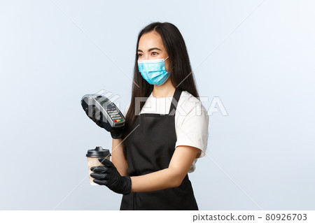 Coffee shop, coronavirus, social distancing and contactless payment concept. Cute asian girl in medical mask working cafe, handing coffee takeaway and POS terminal Coffee shop, coronavirus, social distancing and contactless payment concept. Cute asian girl in medical mask working cafe, handing coffee takeaway and POS terminal 80926703