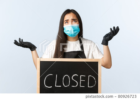Small business, covid-19 pandemic, preventing virus and employees concept. Distressed and sad asian female cafe owner, coffee shop staff complaining on coronavirus lockdown near closed sign 80926723