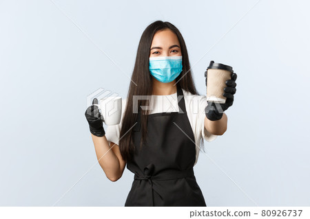 Covid-19, social distancing, small coffee shop business and preventing virus concept. Cute smiling asian barista recommend using takeaway paper cups during coronavirus, handing you drink 80926737