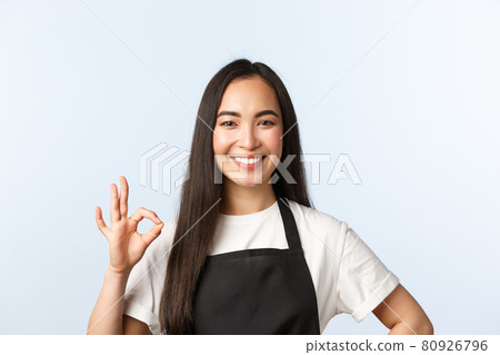 Coffee shop, small business and startup concept. Pleasant cute smiling asian barista, shop or cafe employee in black apron guarantee quality of service, show okay sign, recommend place Coffee shop, small business and startup concept. Pleasant cute smiling asian barista, shop or cafe employee in black apron guarantee quality of service, show okay sign, recommend place 80926796