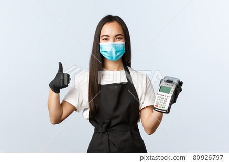 Small business, coronavirus, social distancing and contactless payment concept. Asian barista, waitress in cafe, medical mask and gloves, recommend use POS terminal for safe purchase during covid-19 Small business, coronavirus, social distancing and contactless payment concept. Asian barista, waitress in cafe, medical mask and gloves, recommend use POS terminal for safe purchase during covid-19 80926797