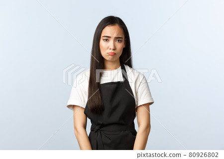 Coffee shop, small business and startup concept. Gloomy and sad cute asian barista, female cafe staff sulking, feeling distressed or exhausted, have unhappy expression, white background 80926802