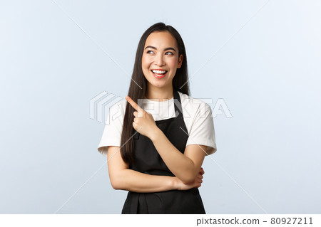 Coffee shop, small business and startup concept. Cheerful smiling asian female barista at cafe counter, wear black apron, pointing and looking upper left corner joyful, showing promo Coffee shop, small business and startup concept. Cheerful smiling asian female barista at cafe counter, wear black apron, pointing and looking upper left corner joyful, showing promo 80927211