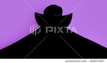 Man in dracula costume stands with his back in black cloak 80927407