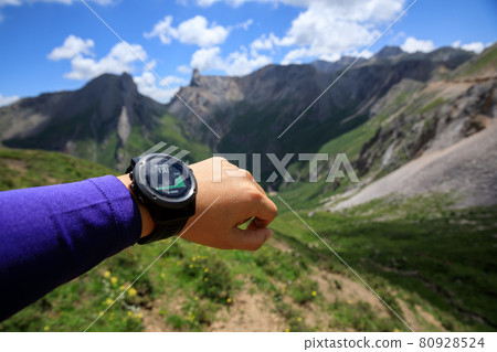 Hiker on high altitude mountain top checking the altimeter on the sports watch 80928524