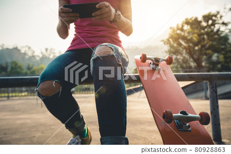 Skateboarder use mobile phone at skatepark 80928863