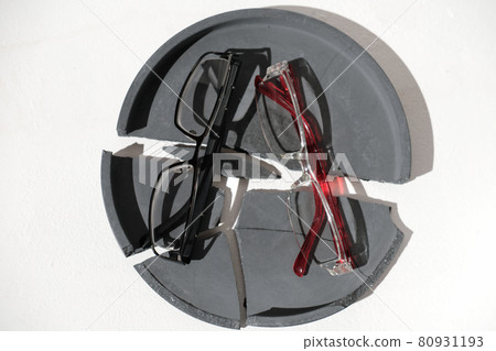 eyeglasses on a broken crashed cement tray. crackled concrete plate and two glasses, top view. eye sight and correction concept. optics store. 80931193