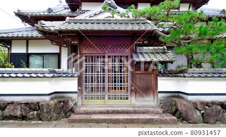 歷史悠久的農舍的入口。土牆和門是石頭。 歷史悠久的農舍的入口。土牆和門是石頭。 80931457