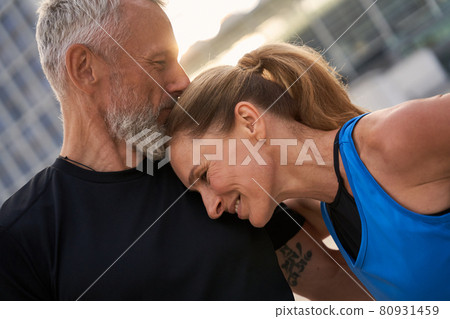 Portrait of affectionate middle aged couple, man and woman in sportswear having morning workout in the city on a summer day Portrait of affectionate middle aged couple, man and woman in sportswear having morning workout in the city on a summer day 80931459