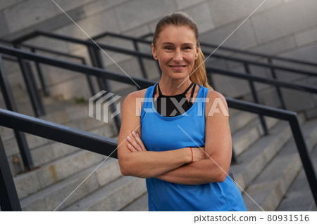 Portrait of smiling mature woman in sportswear posing outdoors after training in the city 80931516
